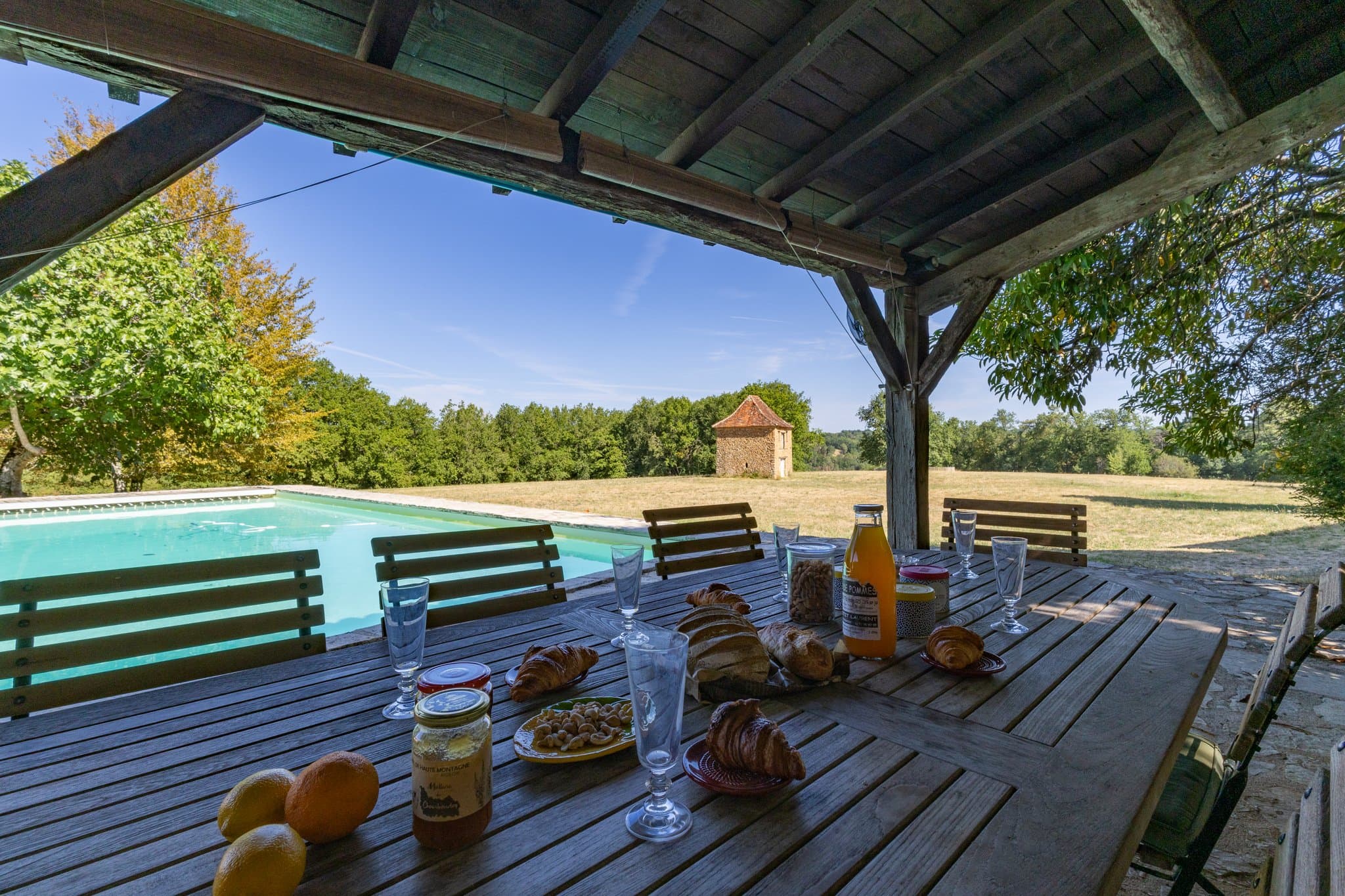 Breakfast on the covered terrace by the pool, with the pigeonnier in the meadow beyond.