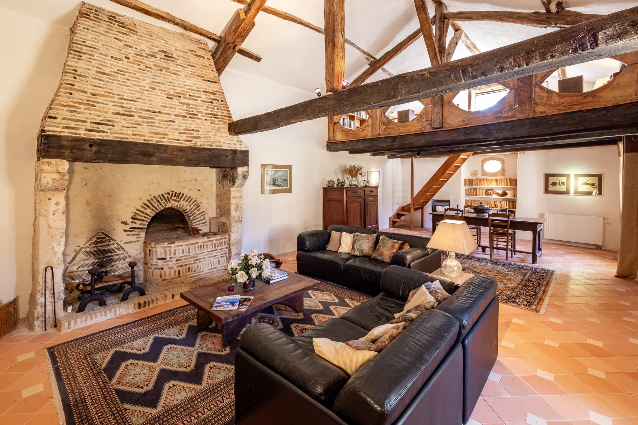 The living room at The Friends' House, under its cathedral roof: brick fireplace and bread oven, exposed beams and mezzanine.